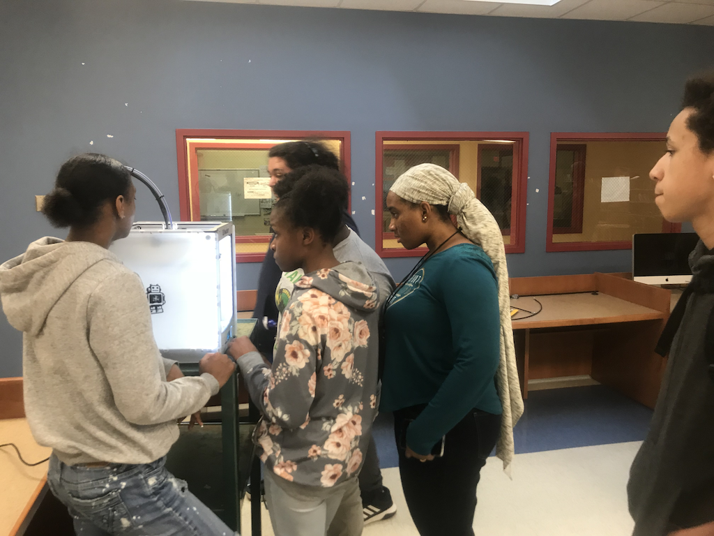 Students watching laser cutter burn their project pic. Courtesy of the author.
